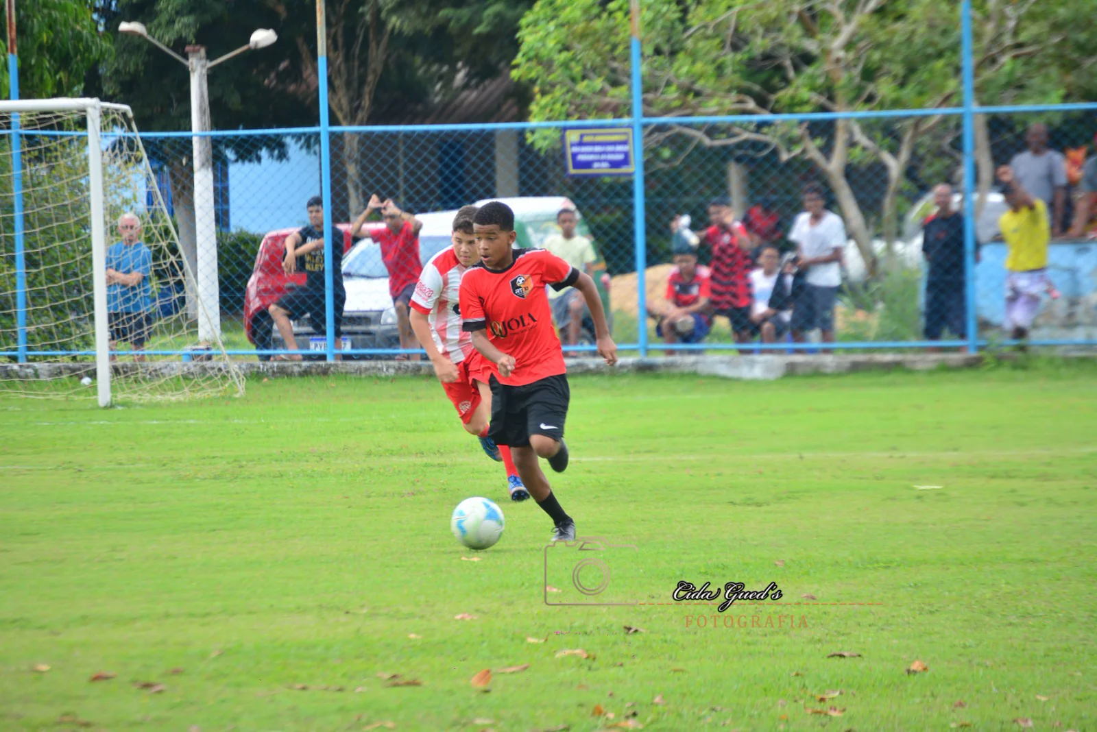 Jovem conduzindo a bola em uma partida no Campo do Aliança